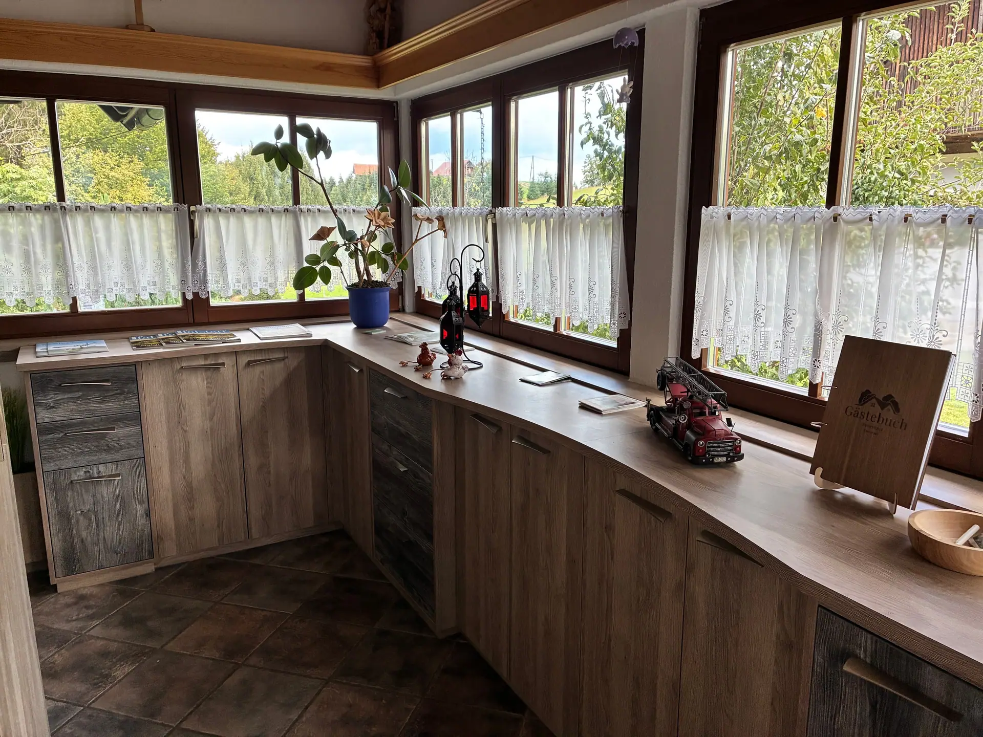 Raum mit umlaufender Fensterfront und Anrichte aus Holz