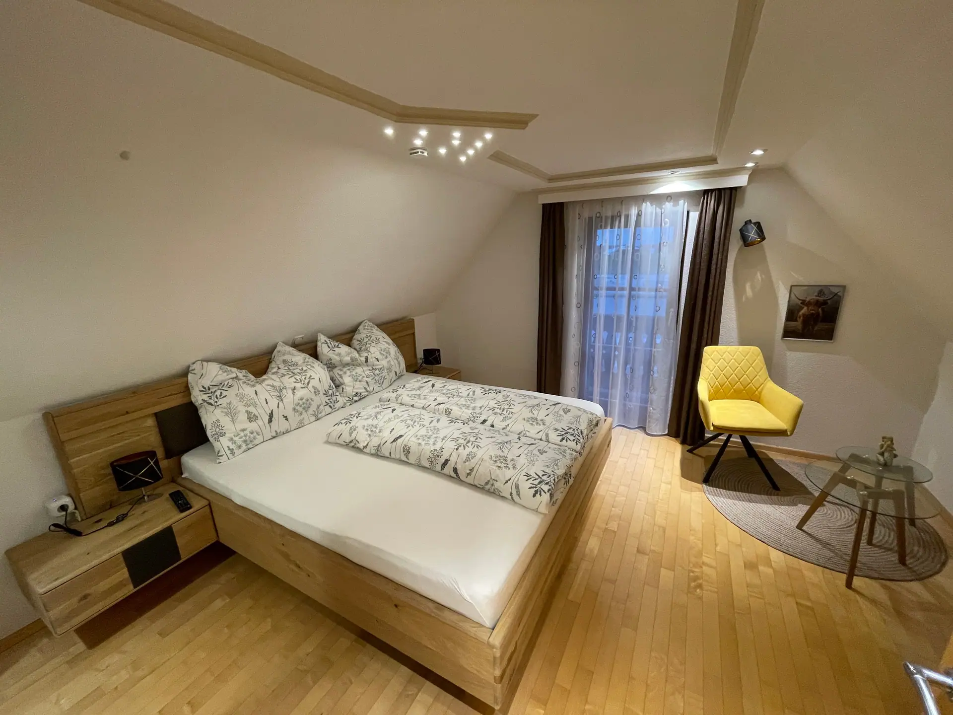 Schlafzimmer mit Doppelbett unter der Dachschräge, gelber Sessel am Fenster