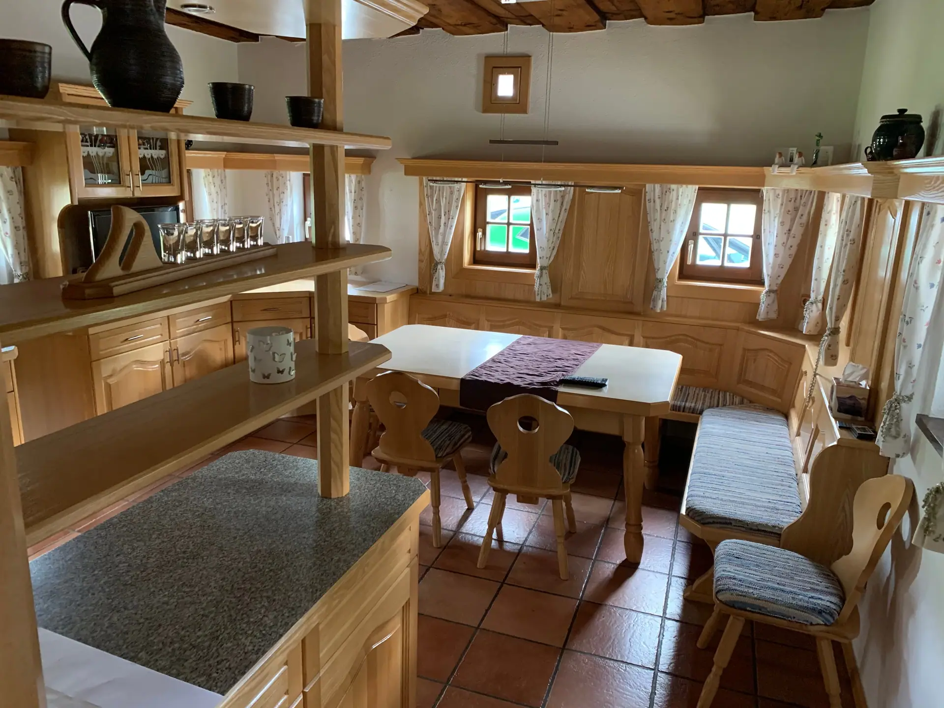Stube mit Holzregalen, Esstisch, Eckbank und Stühlen mit Herzmotiv